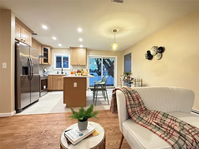 a kitchen with stainless steel appliances granite countertop a sink a stove a refrigerator cabinets and chairs