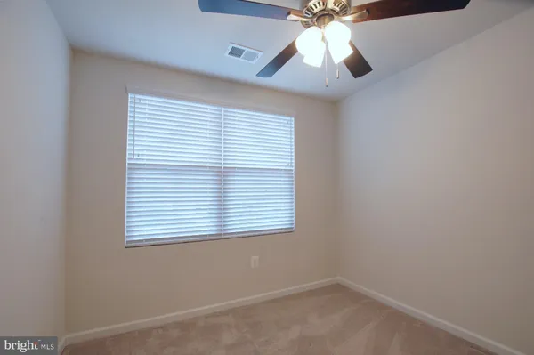 an empty room with a window and a fan