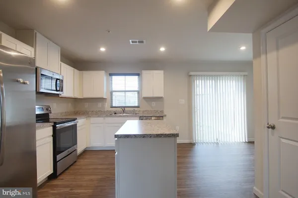 a large kitchen with granite countertop a large counter top a sink stainless steel appliances and cabinets