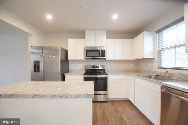 a kitchen with granite countertop a refrigerator stove top oven and sink