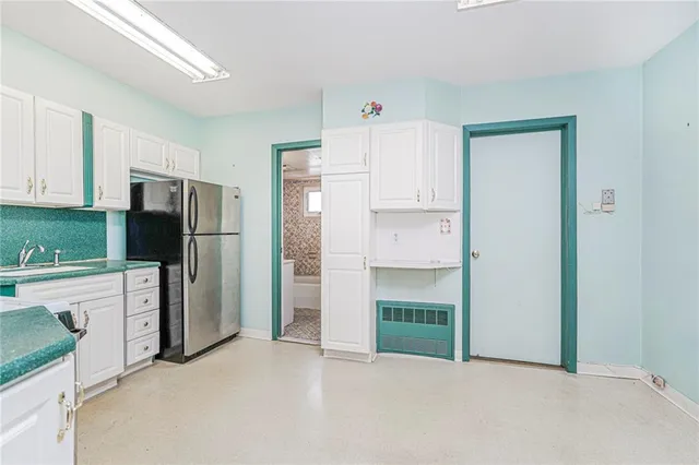 a kitchen with white cabinets and refrigerator