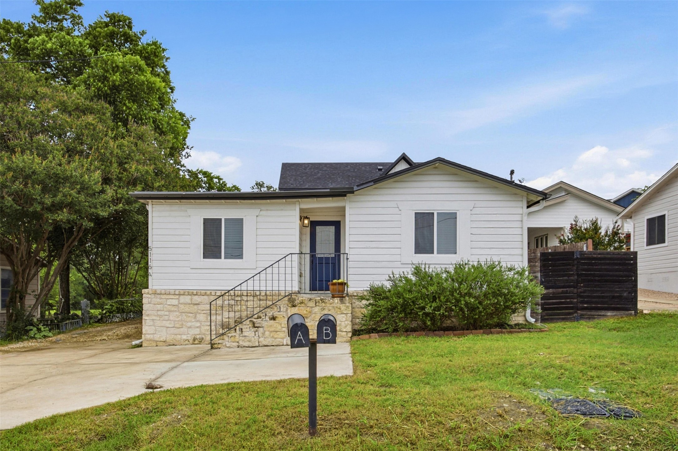 5116 Heflin Lane, Unit 1 Austin, TX 78721 - Photo 3 of 35 A charming cottage-style home with a welcoming blue door and neatly maintained landscaping awaits.