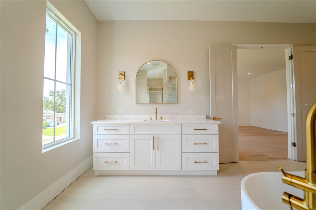 4502 South Shamrock Road Tampa, FL 33611 - Photo 33 of 41 a bathroom with a double vanity sink a mirror and a bathtub