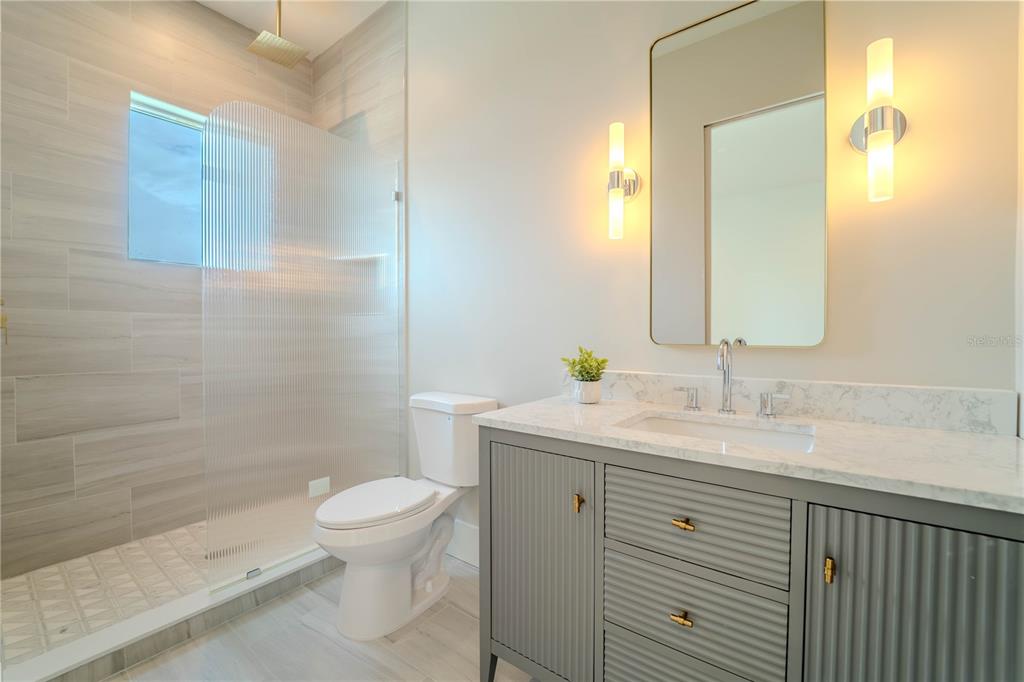 4502 South Shamrock Road Tampa, FL 33611 - Photo 38 of 41 a bathroom with a granite countertop sink a toilet and a mirror