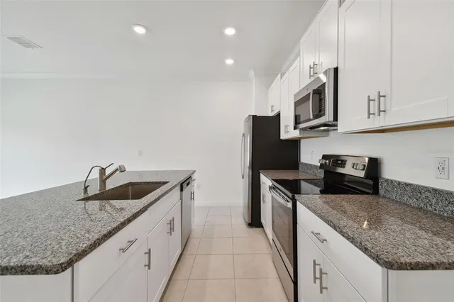 a kitchen with granite countertop a refrigerator a stove a sink a microwave and cabinets