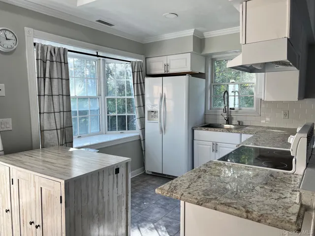 a kitchen with stainless steel appliances granite countertop a refrigerator a sink a stove and island