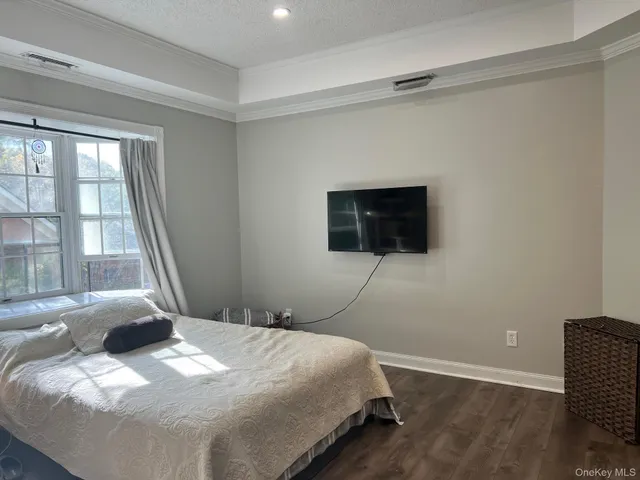 a bedroom with a bed and a flat tv screen on dresser
