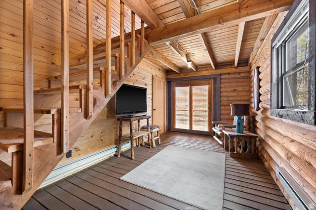 4725 Pine Ridge Road Evanston, UT 82930 - Photo 44 of 82 Wood-paneled interior featuring an open staircase with wood railings, exposed wood beam ceiling, and wood-finish flooring