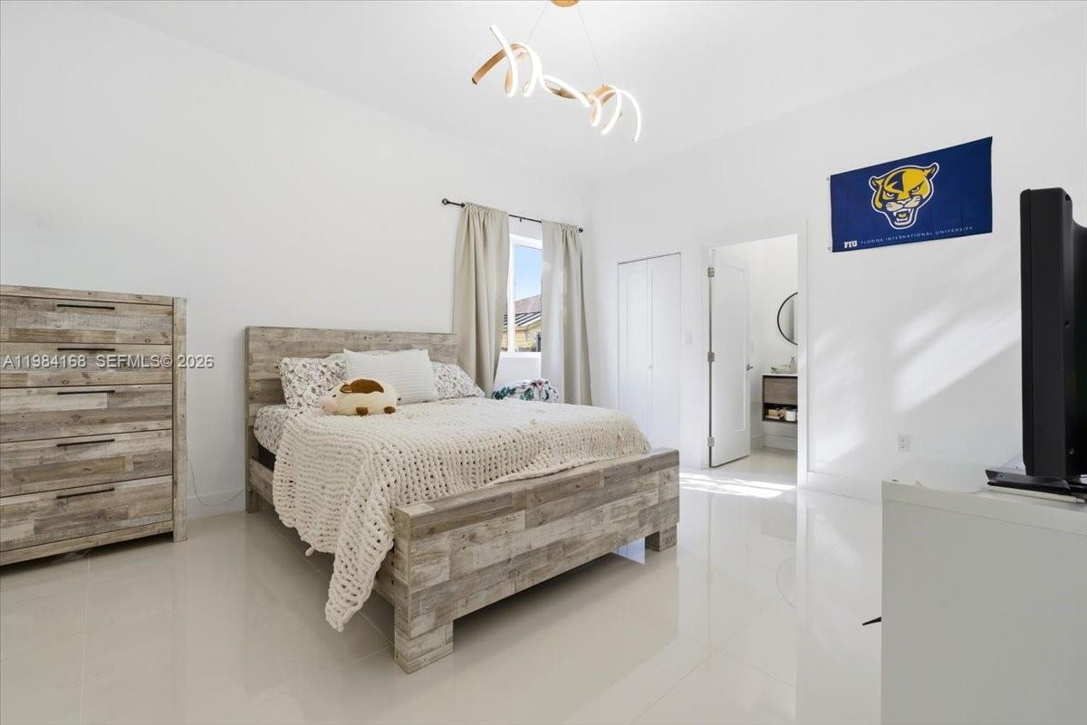 21205 Ingraham Ave Road Cutler Bay, FL 33189 - Photo 32 of 42 a spacious bedroom with a bed and a flat screen tv