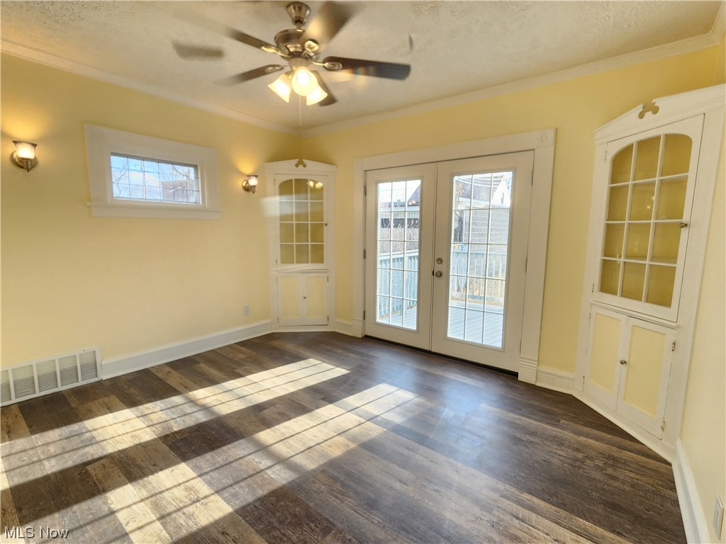 17814 Crestland Road Cleveland, OH 44119 - Photo 10 of 49 Spare room featuring a textured ceiling, crown molding, dark wood-type flooring, ceiling fan, and french doors