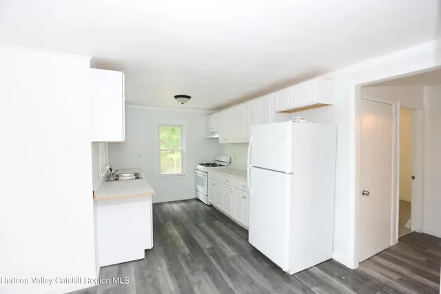 a kitchen with a refrigerator a sink and dishwasher with wooden floor