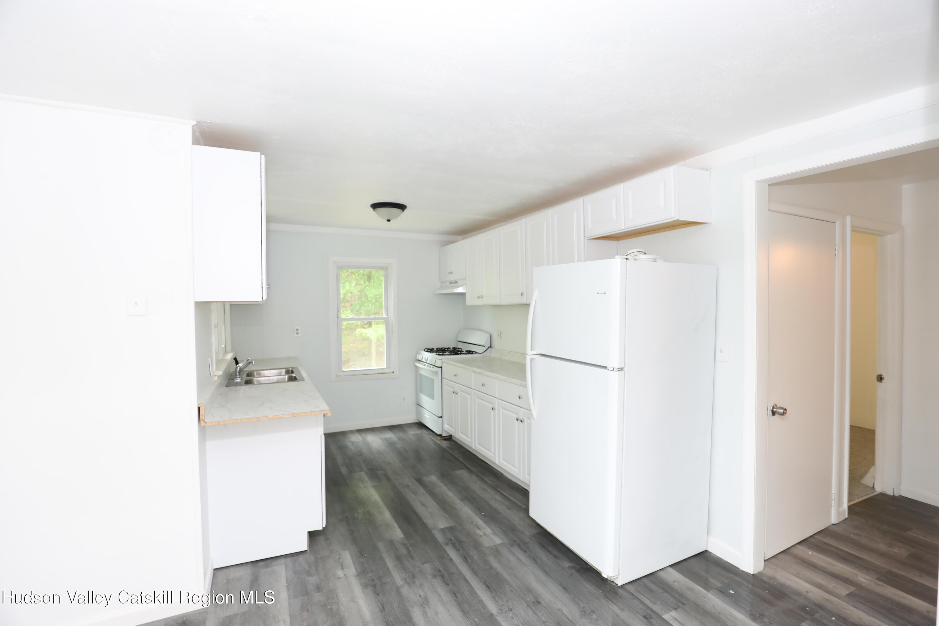 17 Rear Chapel Street, Unit 2 Ellenville, NY 12428 - Photo 7 of 20 a kitchen with a refrigerator a sink and dishwasher with wooden floor