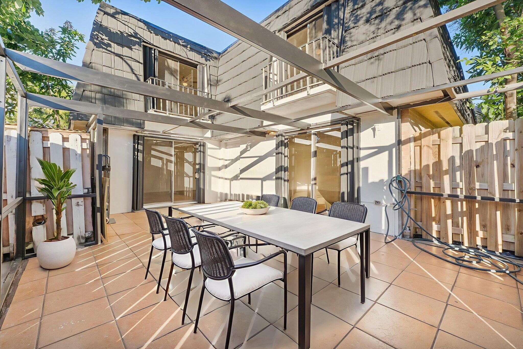 291 Woodland Road Palm Springs, FL 33461 - Photo 32 of 32 a view of a patio with a table and chairs and potted plants