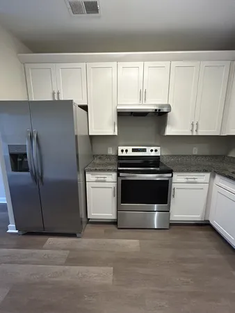 a kitchen with granite countertop white cabinets and stainless steel appliances