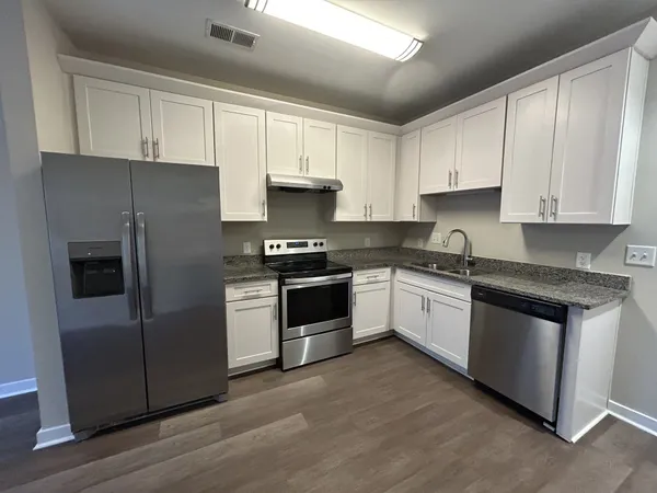 a kitchen with granite countertop white cabinets and stainless steel appliances
