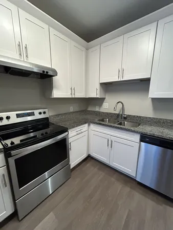 a white kitchen with granite top and stainless steel appliances