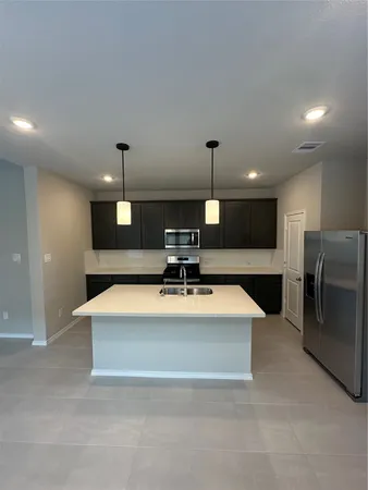 a large kitchen with stainless steel appliances a large counter top a fireplace and a chandelier