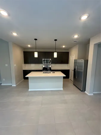 a large hall with stainless steel appliances kitchen island a large tub a sink and a refrigerator