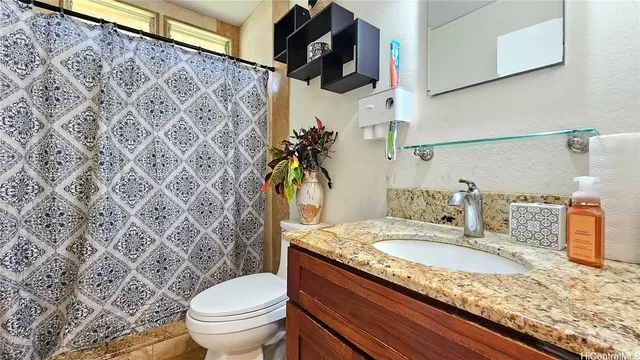 a bathroom with a granite countertop sink and a toilet