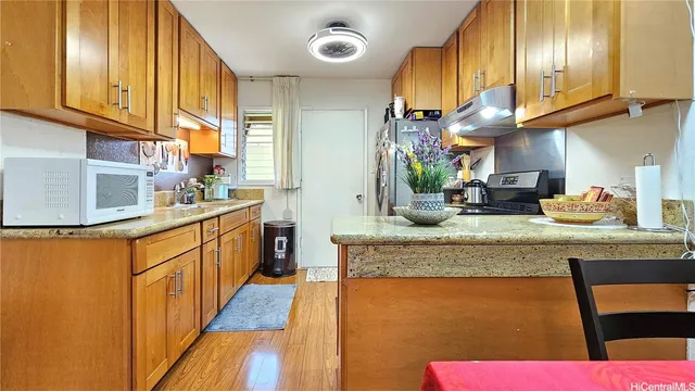 a kitchen with stainless steel appliances granite countertop wooden cabinets a sink dishwasher and a fireplace with wooden floor