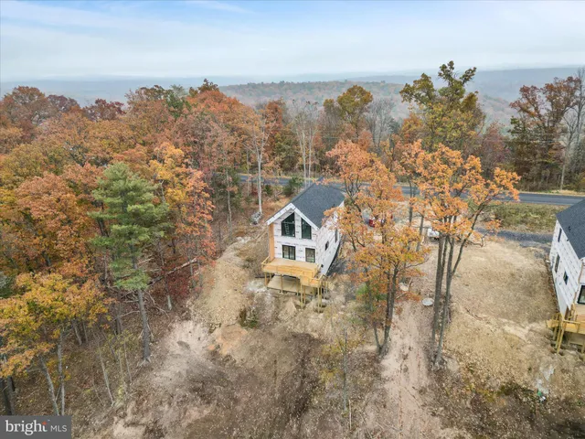 a front view of a house with a yard and mountain view in back