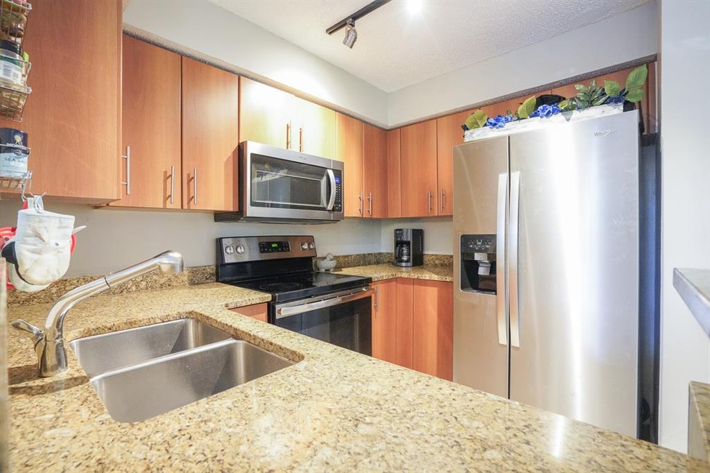 1011 Crystal Way, Unit P Delray Beach, FL 33444 - Photo 7 of 28 a kitchen with granite countertop a refrigerator sink and microwave