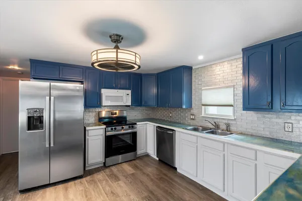 a kitchen with stainless steel appliances granite countertop a sink a stove a refrigerator cabinets and a window