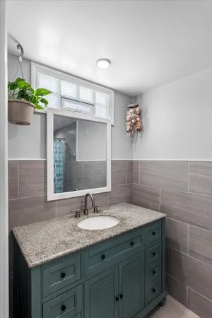 a bathroom with a granite countertop sink a mirror and a shower