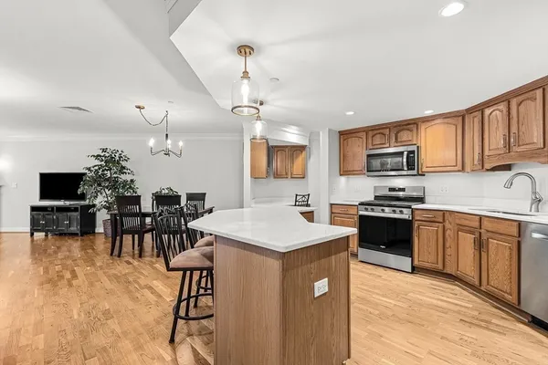 a kitchen with stainless steel appliances granite countertop a stove top oven a sink dishwasher a dining table and chairs with wooden floor