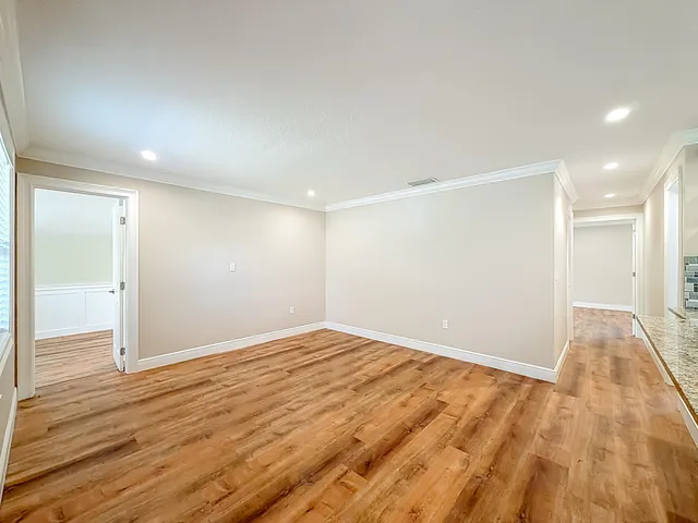 a view of kitchen and empty room with wooden floor