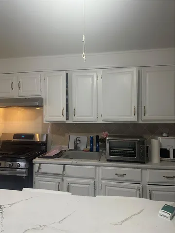 a kitchen with white cabinets and appliances