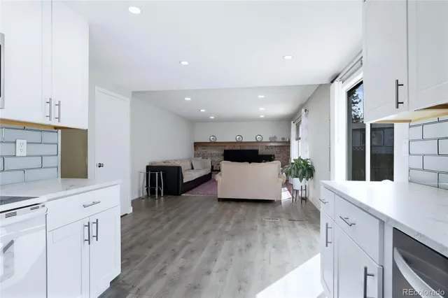 a large white kitchen with lots of counter space wooden floor and stainless steel appliances