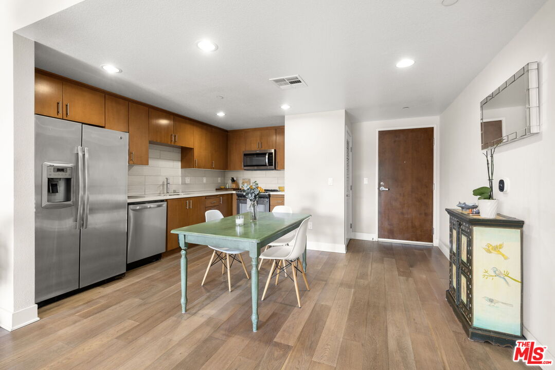 13337 Beach Avenue, Unit 406 Marina del Rey, CA 90292 - Photo 5 of 23 a kitchen with stainless steel appliances kitchen island granite countertop a refrigerator a stove a sink a dining table and chairs with wooden floor