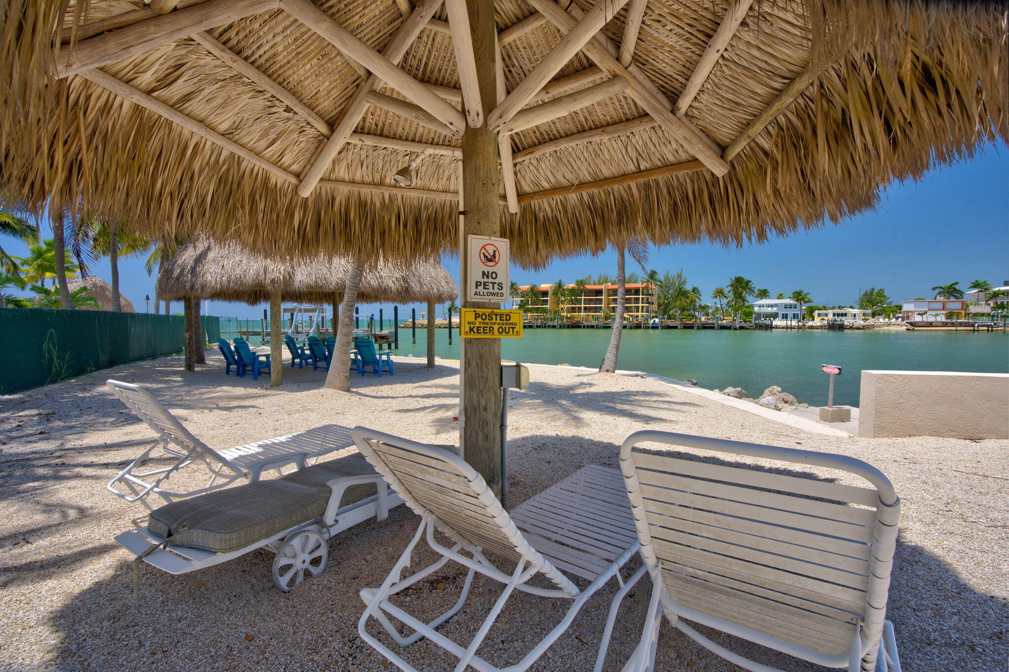 2000 Coco Plum Drive, Unit 1202 Marathon, FL 33050 - Photo 35 of 44 a view of a patio with a table and chairs under an umbrella with palm trees