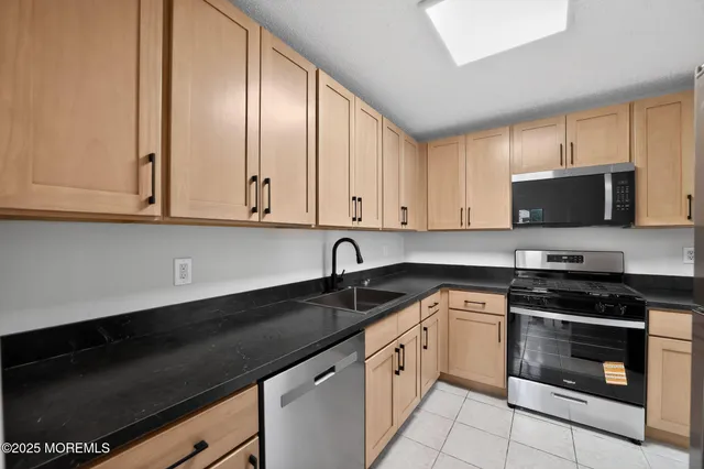a kitchen with granite countertop white cabinets stainless steel appliances and a sink