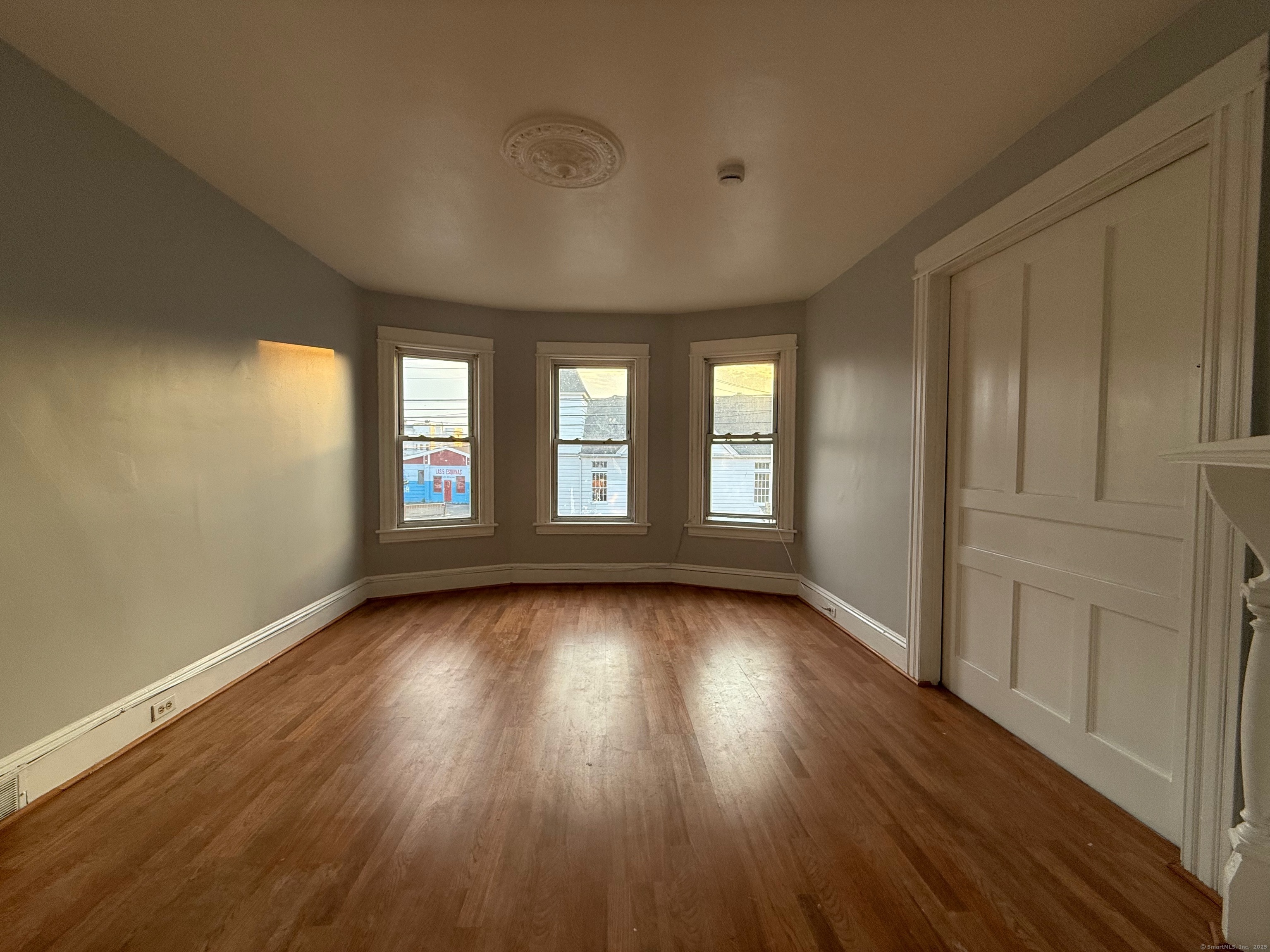 a view of an empty room with wooden floor and a window