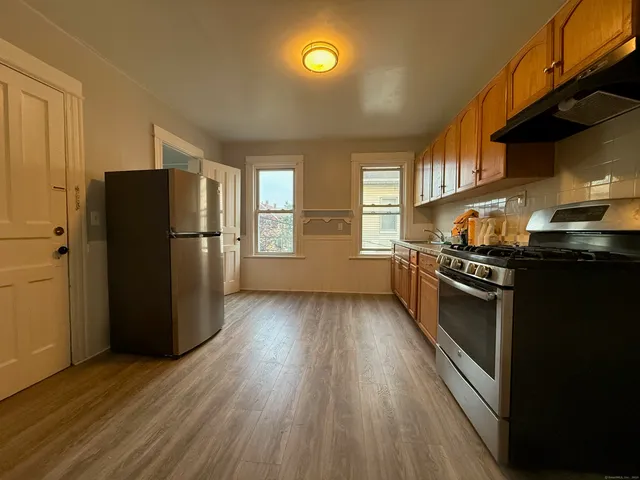 a kitchen with stainless steel appliances granite countertop a refrigerator a stove and a wooden floors