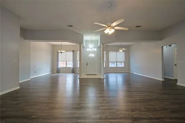 a view of an empty room with window and wooden floor