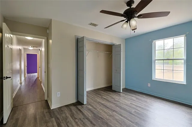 a view of empty room with wooden floor and fan