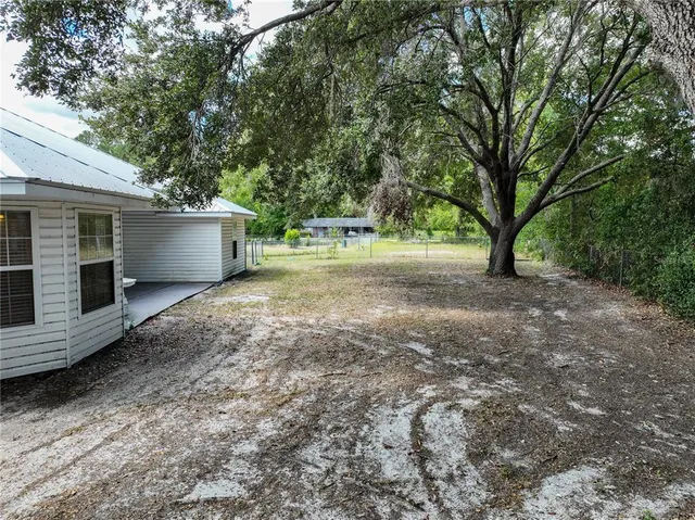 a view of a house with backyard and trees