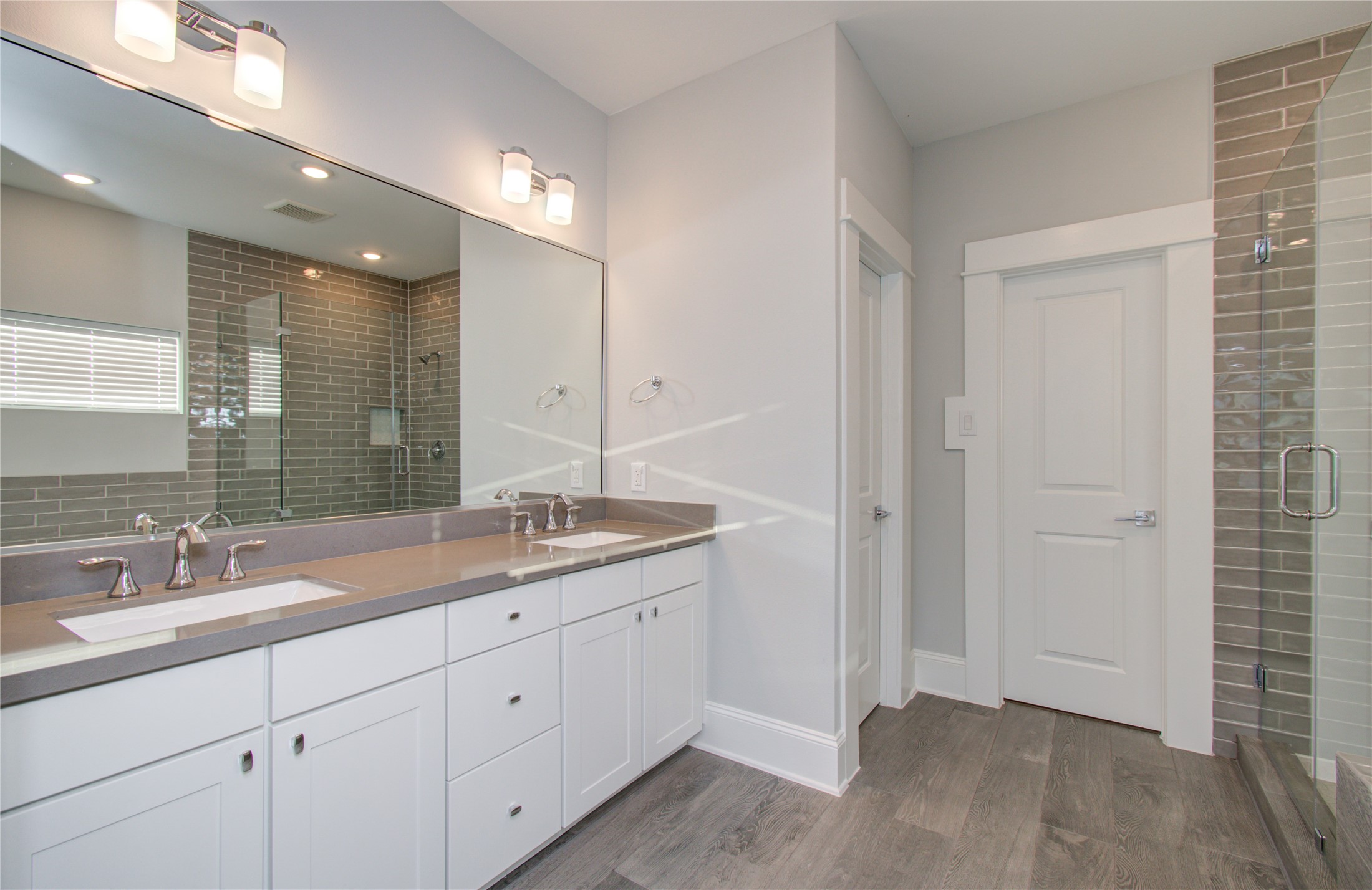 1262 North Post Oak Road, Unit A Houston, TX 77055 - Photo 39 of 50 Another perspective of the primary bathroom showcases the full length of the dual-sink vanity, complete with dark gray quartz countertops and modern lighting fixtures. Dark wood-look tile runs throughout the space.