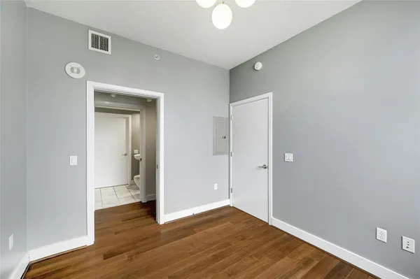 a view of an empty room with wooden floor and a bathroom