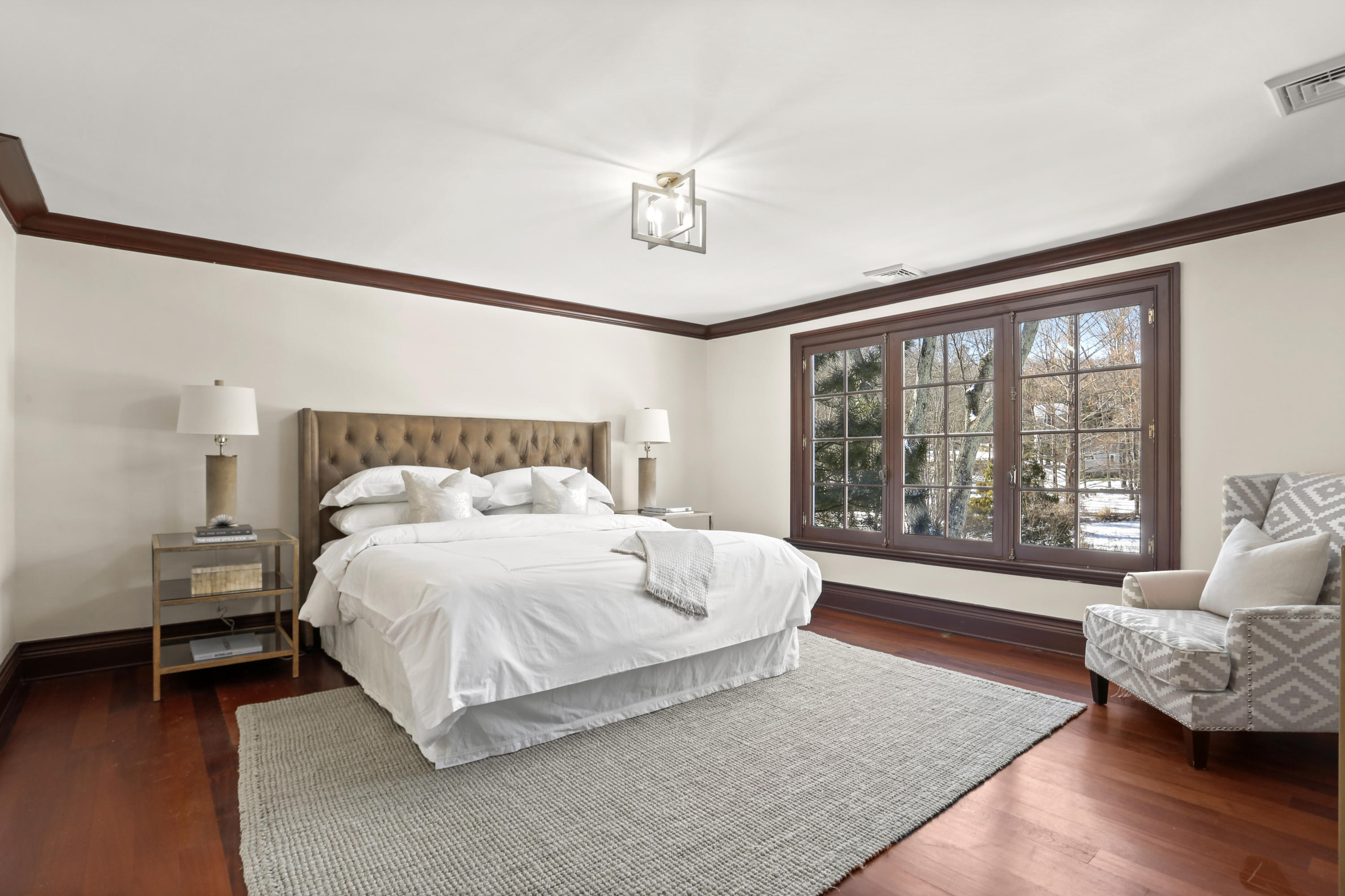89 Dabney Road New Canaan, CT 06840 - Photo 25 of 40 a spacious bedroom with a bed a couch and a large window with wooden floor