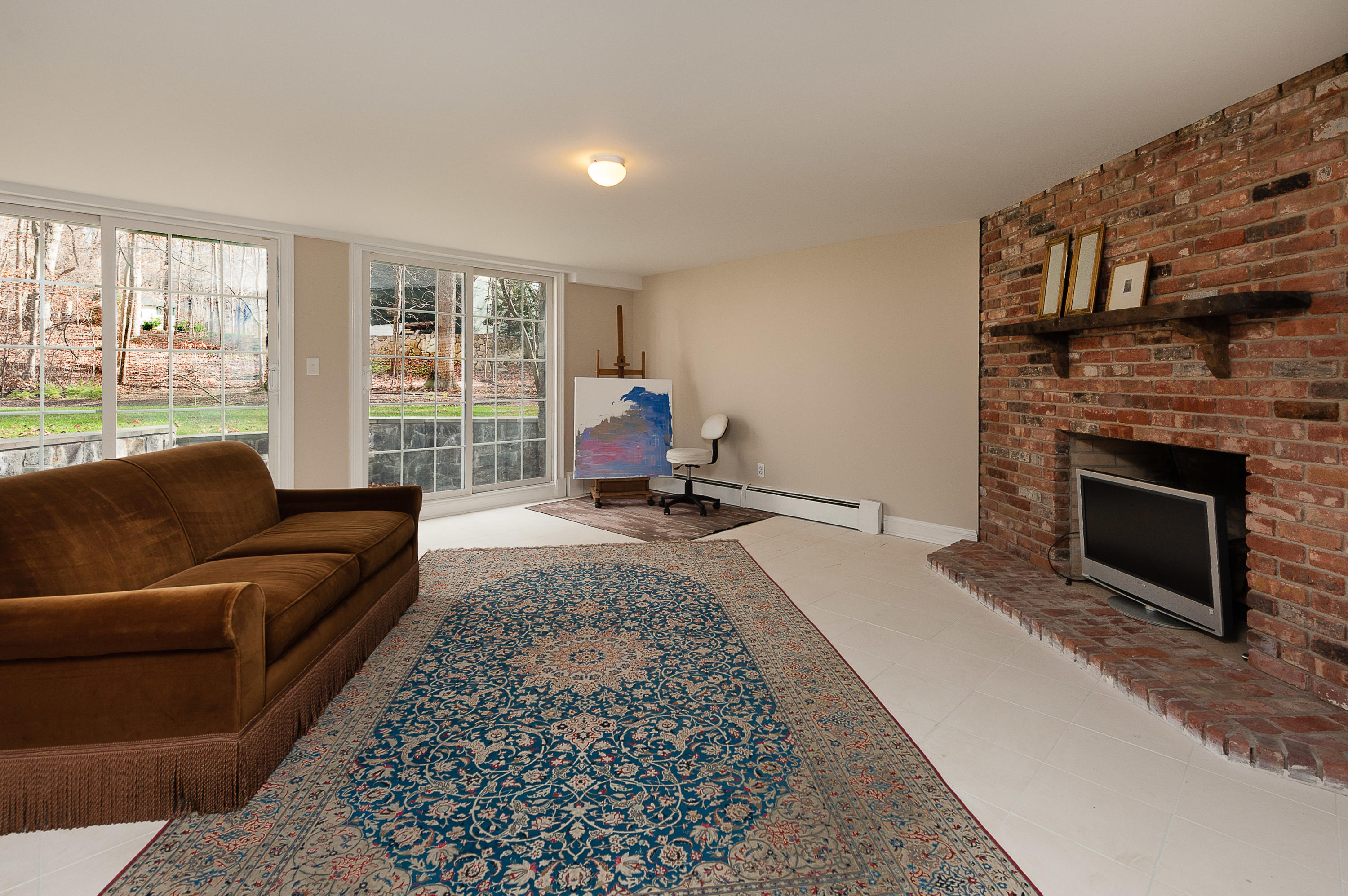 89 Dabney Road New Canaan, CT 06840 - Photo 34 of 40 a living room with a couch a rug a fireplace and a large window