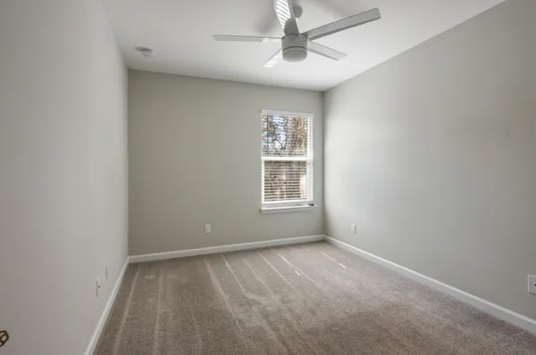 an empty room with a window and a fan