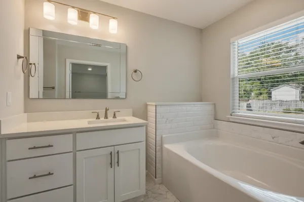 a bathroom with a tub sink and mirror