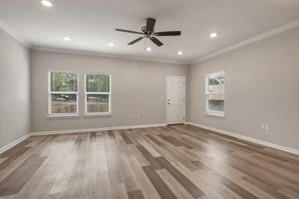 a view of an empty room with a window and wooden floor