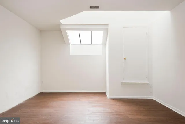 an empty room with wooden floor and window