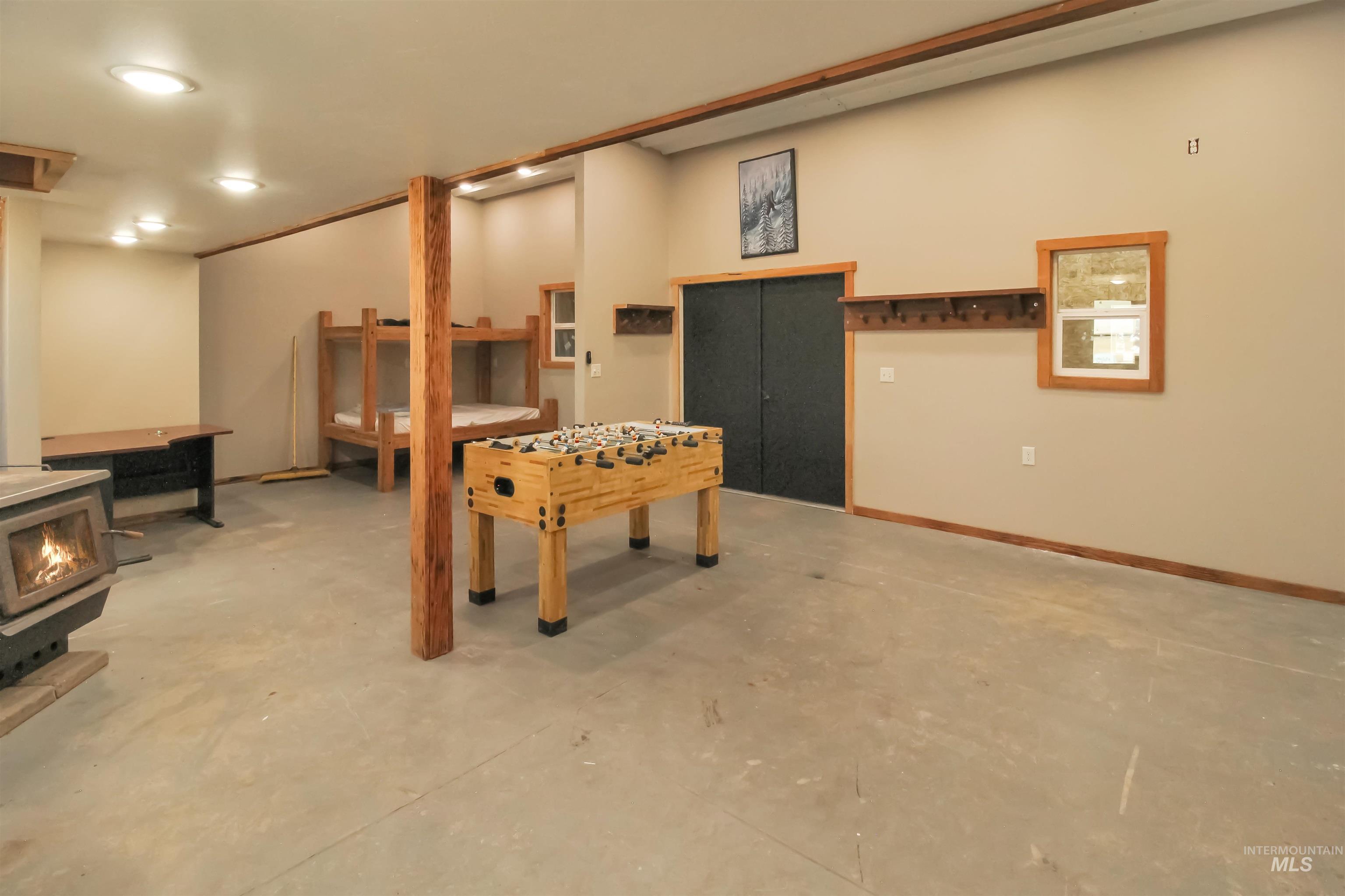 2469 Hague Road Midvale, ID 83645 - Photo 33 of 50 Spacious lower-level room featuring a wood-burning stove on a stone hearth, exposed wood beams, and recessed lighting