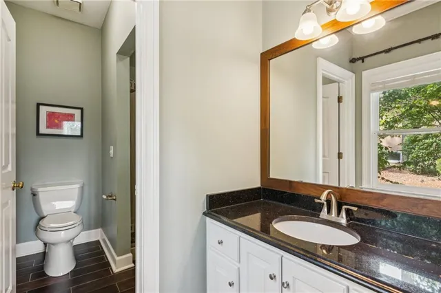 a bathroom with a granite countertop sink a toilet and a mirror